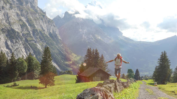 istock Hiker balances as he walks down rock wall near road 1334919478