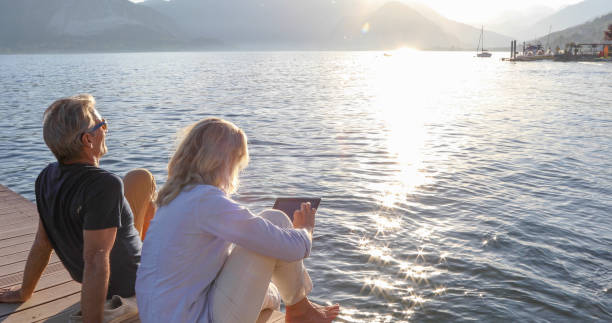 istock Mature couple relax on dock over water, at sunrise 1334920665