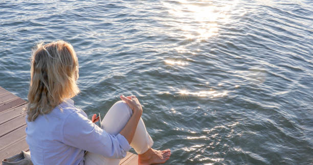 istock Woman relaxes on dock over water, at sunrise 1334920686