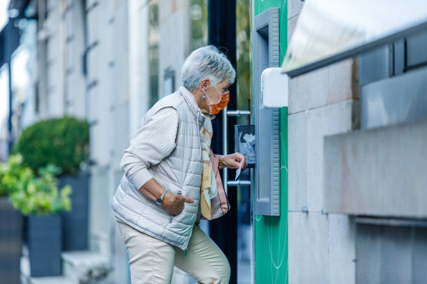 istock An Older Woman with Face Mask is Using ATM. 1334923474