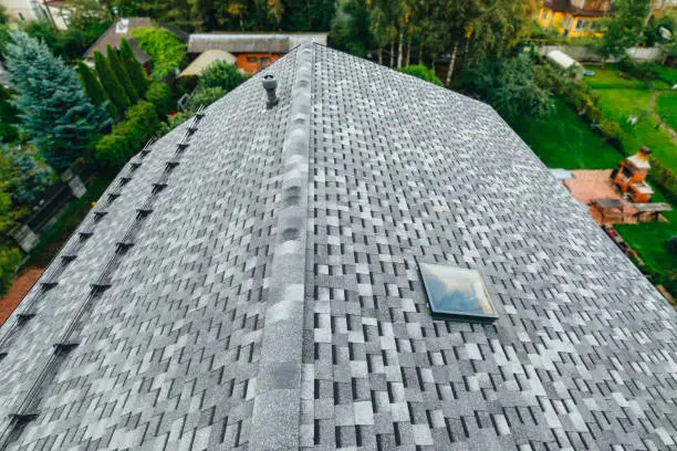 roof of new house with shingles roof-tiles, ventilation window and snow retention system