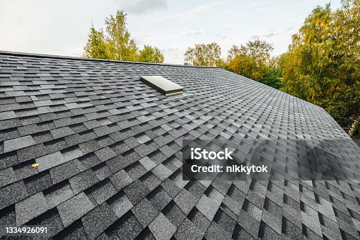 istock roof of new house with shingles roof-tiles and ventilation window 1334926091