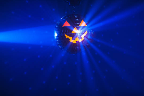 istock Halloween party pumpkin disco ball, blue shiny rays background 1334926124