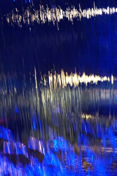 abstract colored lights reflected on water vertical background pattern - blue streak lights imagens e fotografias de stock
