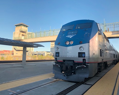 A train platform with railway tracks either side of it in Toulouse, France. There is a train on one of the tracks, arriving at the station and ready to pick up passengers.