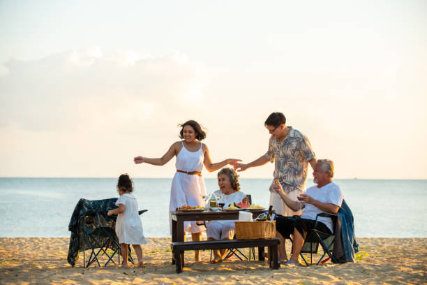 eine gruppe asiatischer familien mit mehreren generationen genießen bei sonnenuntergang eine gemeinsame dinnerparty am strand. - family grandmother multi generation family nature stock-fotos und bilder