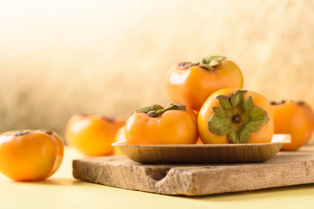 плоды хурмы на золотистом фоне - persimmon стоковые фото и изображения