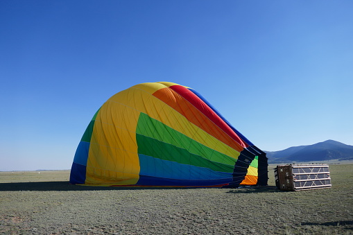 Deflated rainbow colored hot air balloon laying on side