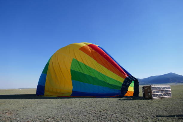 Deflated rainbow colored hot air balloon laying on side Deflated rainbow colored hot air balloon laying on side deflated stock pictures, royalty-free photos & images