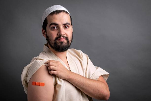 junger muslimischer mann posiert mit einem impfpflaster im arm - studio shot african descent minority looking at camera stock-fotos und bilder