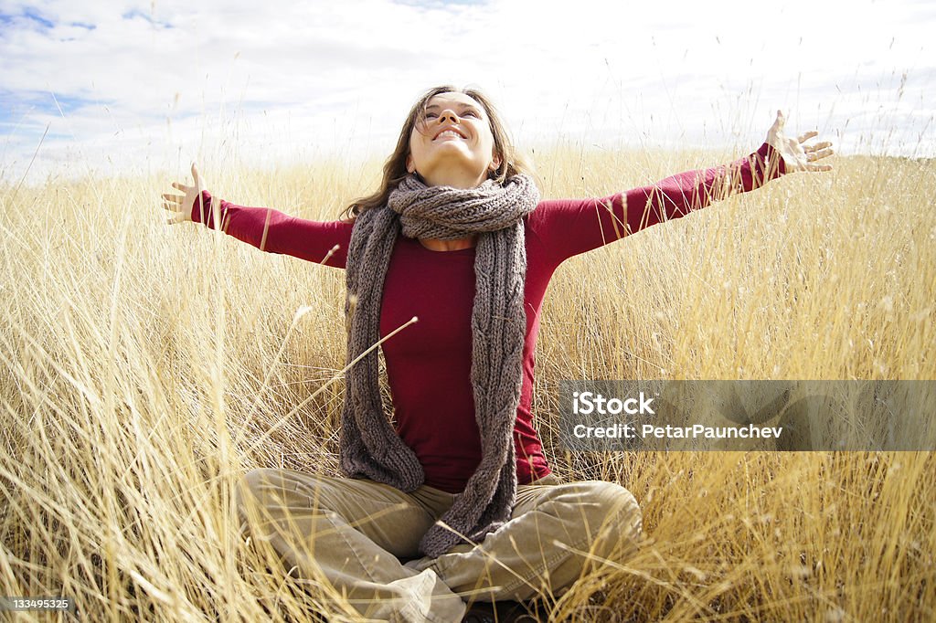 Joyful sunshine Beautiful young woman enjoying sunshine in a field with long grass Adult Stock Photo