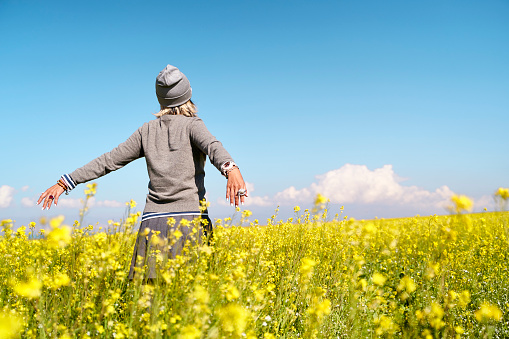 rear view of asian woman tourist embracing nature in a field of canola flowers