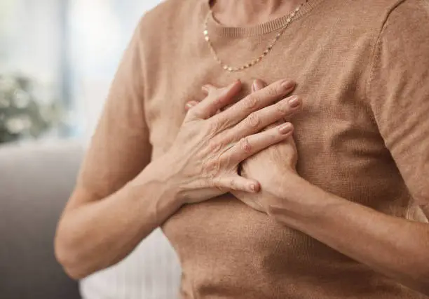 Photo of Shot of an unrecognisable woman experiencing chest pain at home