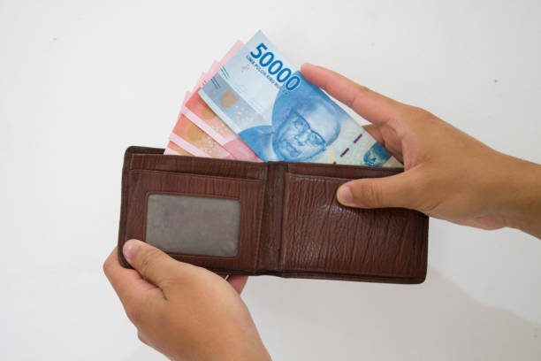 istock Hand holding Indonesian Rupiah (IDR) Red 100,000 bank notes currency from leather wallet on white background. 1334962061