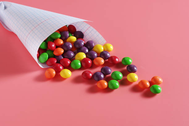 Colorful sweet candy Colorful sweet candy in paper bag on a pink background Skittles stock pictures, royalty-free photos & images