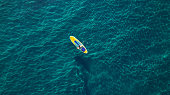 Aerial photo of man on sup board in clear blue sea