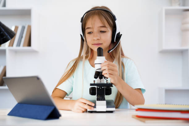 istock Young girl using microscope during online lesson education at home 1334970571
