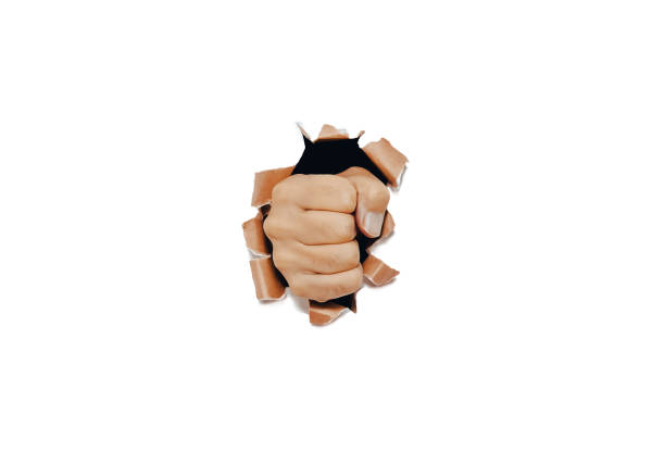 istock Hard fist punching though a white paper wall. Isolated on white background. 1334973057