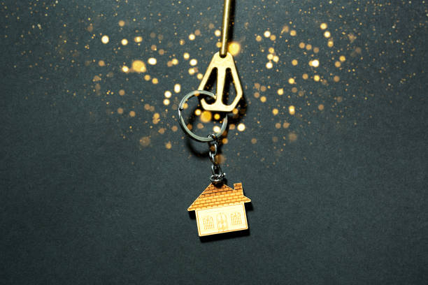 The key to the house with gold sequins and glow on a black background. Building, design, project, moving to new home, mortgage, booking, rent and purchase real estate. New Year, Christmas stock photo