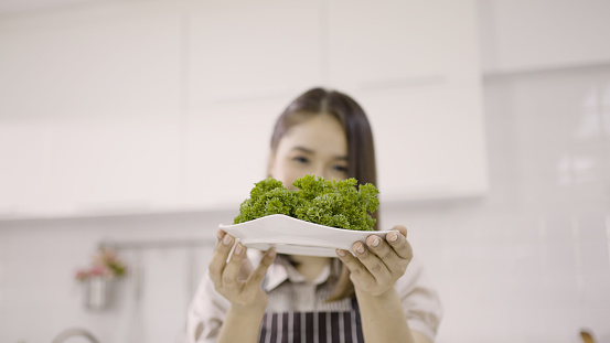 Portrait of woman holding fresh green parsley white ceramic plate.