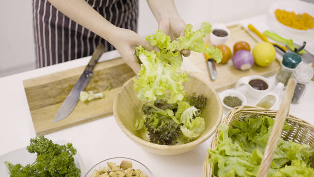 istock Woman's hand breaking up the lettuce leaves in bowl 1334975448