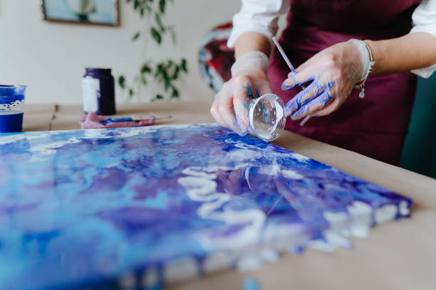 artist mixing acryl paints on the picture working in fluid art technique - pouring imagens e fotografias de stock