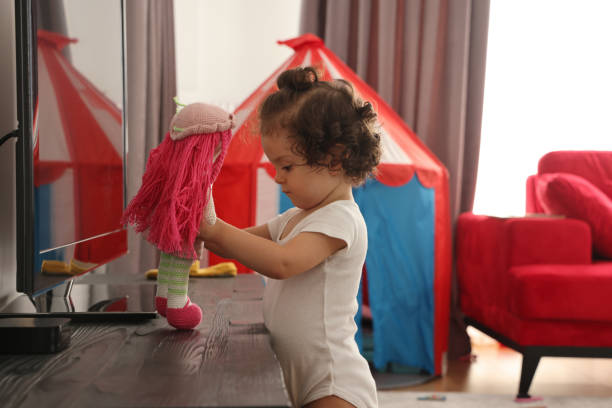 Baby girl playing with doll Baby girl playing with doll buggy eyes stock pictures, royalty-free photos & images