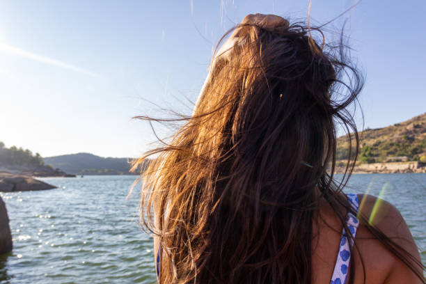 istock Young girl sitting on her back looking at something in a bathing suit. Selective focus. Copy space. 1334985392