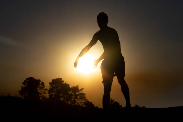 istock Boy holding the sun with his hands against the light. Optical illusion. Copy space. 1334985394