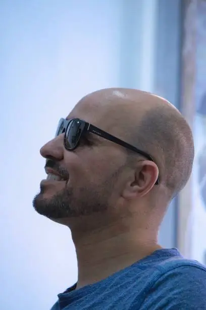 Profile of happy adult bald man in trendy sunglasses smiling and looking away