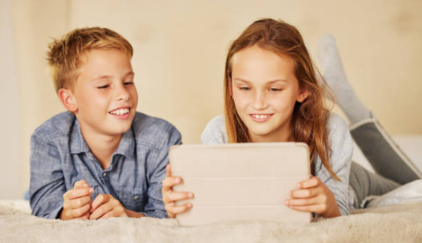 istock Shot of two young children lying on the bed together at home and bonding while using a digital tablet 1334987704