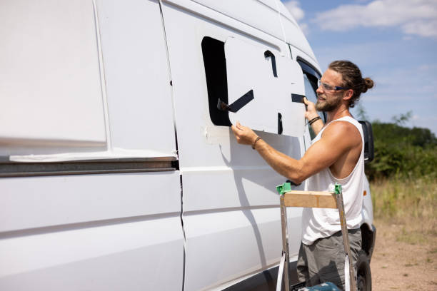 istock Man cut a hole for a window into the side of a van 1334987938
