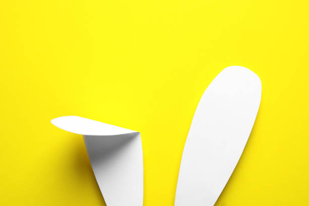 istock Top view of paper bunny ears on yellow background. Easter celebration 1334988698