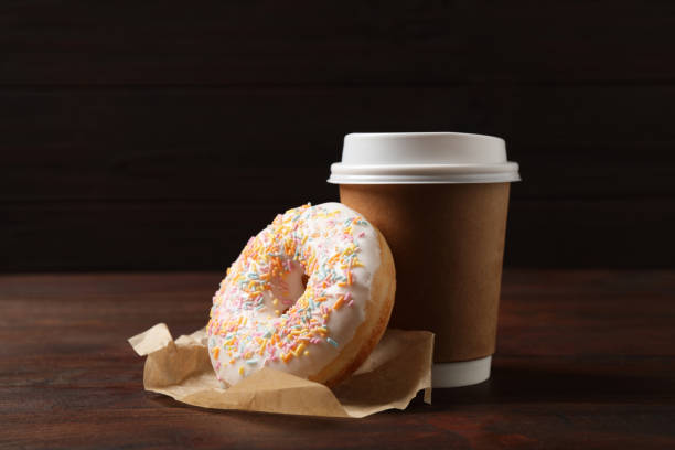 delicioso donut y taza de papel sobre mesa de madera sobre fondo marrón - nobody baking food and drink food fotografías e imágenes de stock