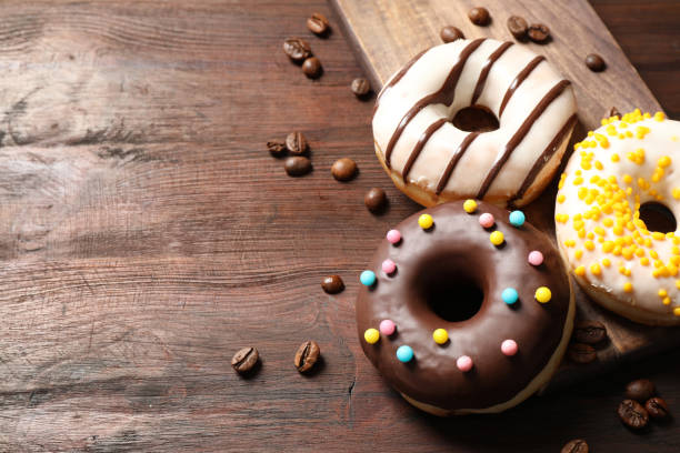 istock Yummy donuts with colorful sprinkles on wooden table, space for text 1334989776