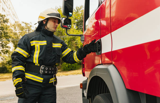 istock One young male firefighter dressed in uniform with protective helmet near fire engine. 1334989878