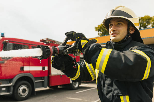 istock One young male firefighter on duty dressed in uniform with water hose extinguishing fire 1334989893