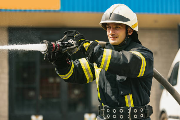 istock One young male firefighter on duty dressed in uniform with water hose extinguishing fire 1334989897