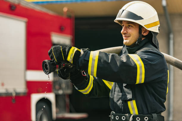 istock One young male firefighter on duty dressed in uniform with water hose extinguishing fire 1334989900