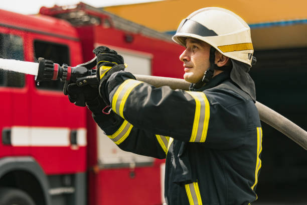 istock One young male firefighter on duty dressed in uniform with water hose extinguishing fire 1334989901