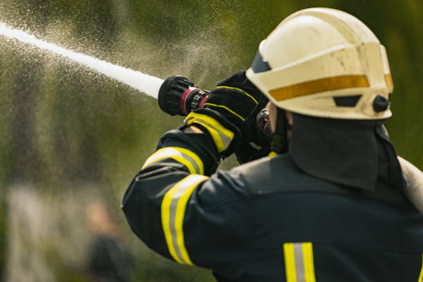 istock One young male firefighter on duty dressed in uniform with water hose extinguishing fire 1334989908