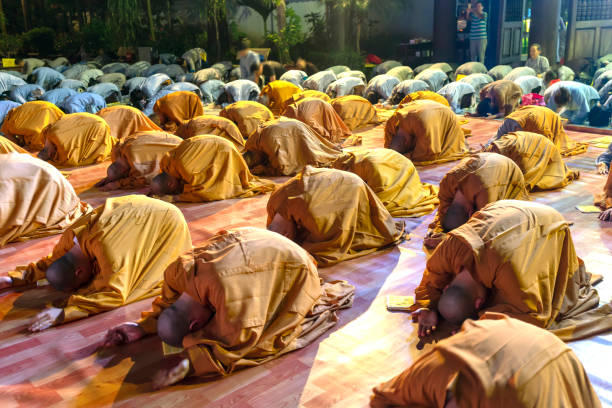 Ho Chi Minh City, Vietnam - December 12th, 2019: Monks and Buddhists are reverently bowing to Buddha during evening ceremony for Amitabha Buddha at an ancient temple in Ho Chi Minh City, Vietnam