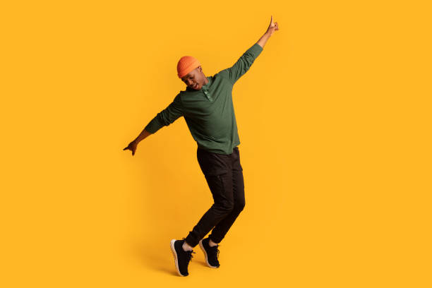 joven y alegre afroamericano de puntillas sobre fondo amarillo - saltar actividad física fotos fotografías e imágenes de stock