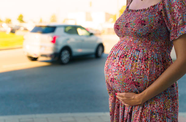Close-up of a pregnant belly with a city street on the background stock photo