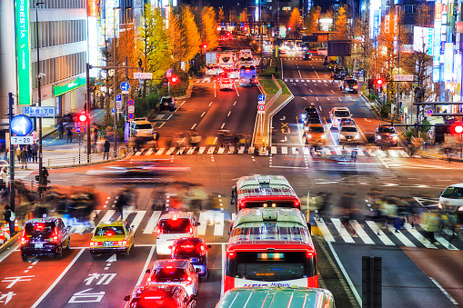 Tokyo, Japan - 2 January 2020: Crowds of unrecognisable blurred people crossing busy city street in Tokyo Shinjuku suburb at night.