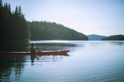 Shot of a young man relaxing on a kayak while fishing