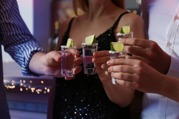 Young people toasting with Mexican Tequila shots in bar, closeup Young people toasting with Mexican Tequila shots in bar, closeup tequila drink stock pictures, royalty-free photos & images
