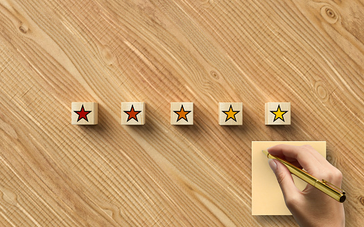 hand writing on a notepad and cubes with 5 star symbols on wooden background