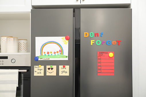Refrigerador moderno con dibujo infantil, notas e imanes en la cocina photo