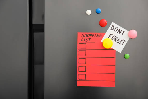 Note with phrase DON'T FORGET, shopping list and magnets on refrigerator, closeup